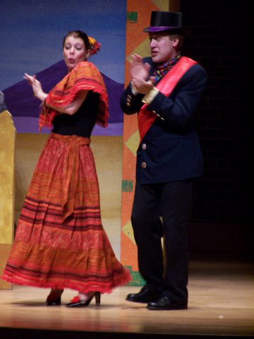 A man and woman in traditional Mexican attire perform on stage